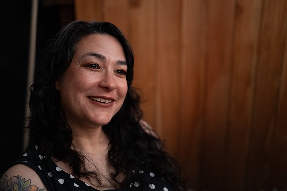a smiling woman sits in front of blurred background