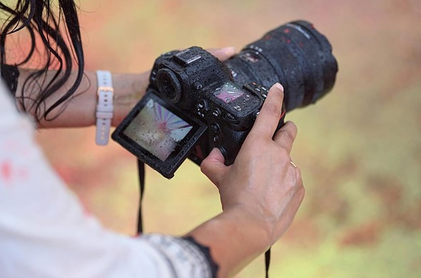 hands hold the nikon z8 covered with water drops over blurred background
