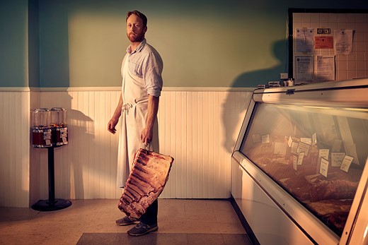 man holds rack of ribs in butcher shop