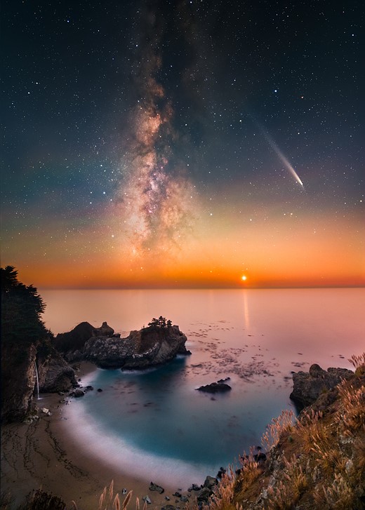 milky way stretches above bay with sandy beach and waterfall