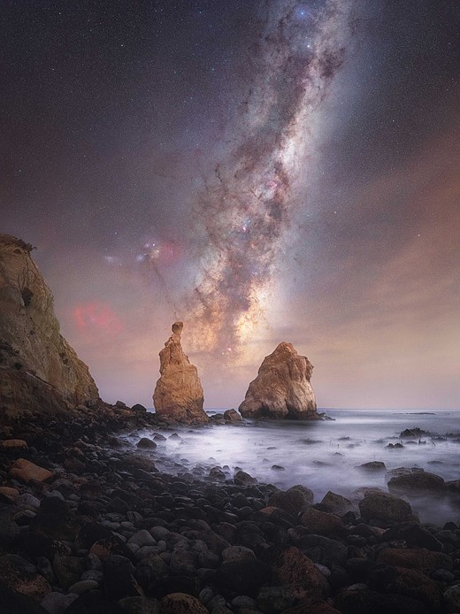 milky way stretches above seaside cliffs