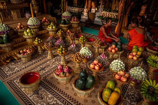 monks sit next to lavish bowls of fruit in temple