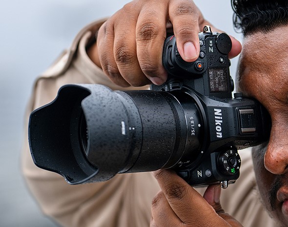 person holds nikon z6III vertical to their eye