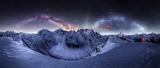 two milky way arches over snowy mountains
