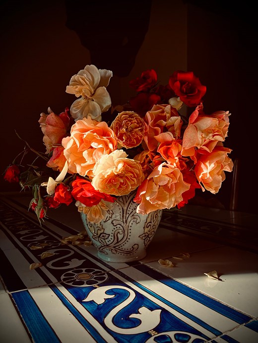 vase of red orange flowers on tile table-CC-Trina O