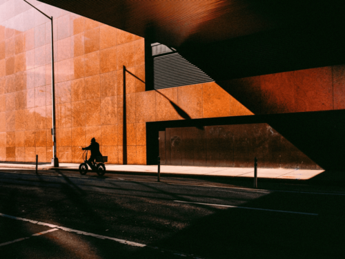 A cyclist rides through deep shadows cast by bold architectural lines, demonstrating visual clarity through sharp contrast and composition.