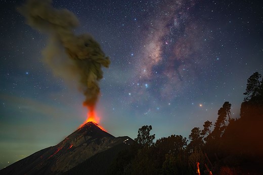 volcano errupts with milky way behind it