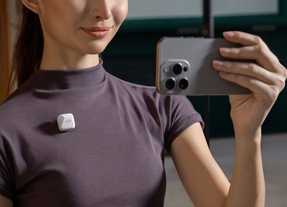 woman holds her phone in front of her with dji mic on her shirt