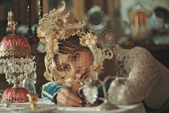 woman with lace floral hat rests head on table