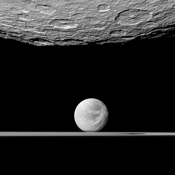 Saturn’s moon Dione  behind Saturn’s edge-on rings