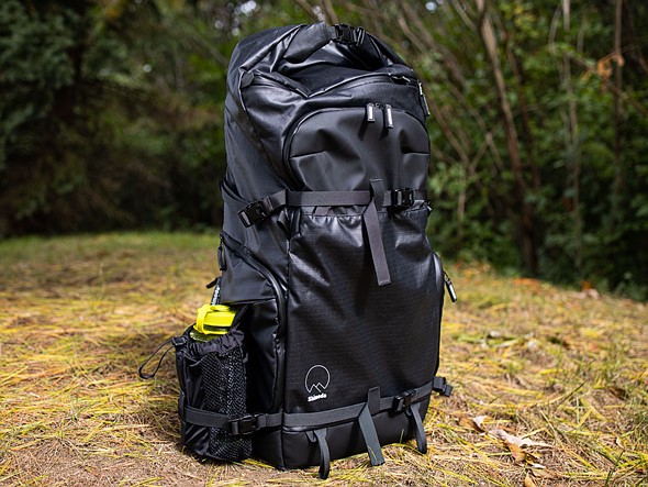 a black backpack sits on ground in forest