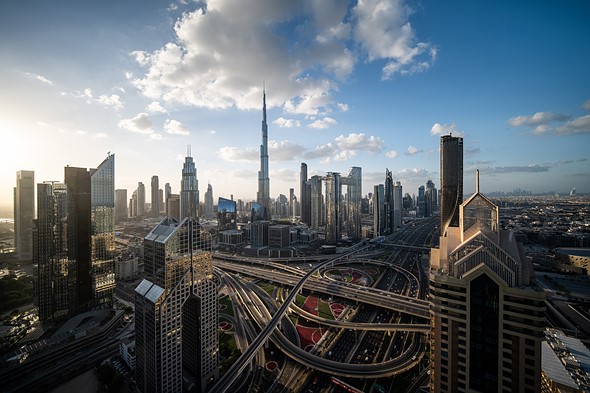 a cityscape expands beneath a blue sky with few clouds