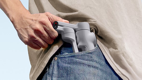 a hand puts the insta360 flow 2 gimbal in a jeans pocket