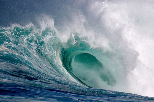 a large wave curls over with water spraying