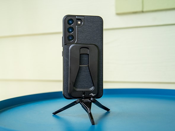 a phone is propped on a blue table with a peak design tripod