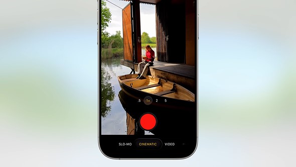 half an iphone with camera app up is placed on blue green faded background