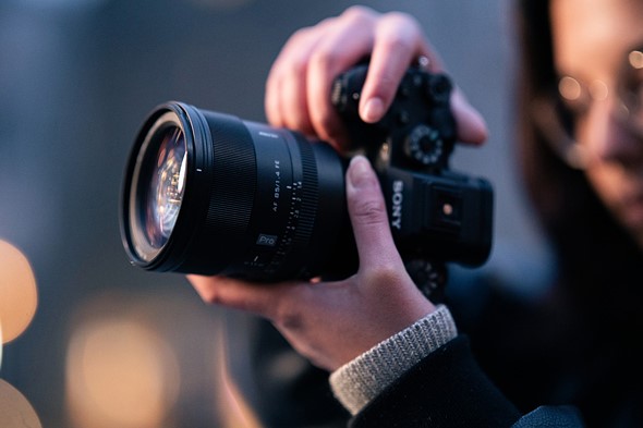 hands hold a sony camera with viltrox lens in front of blurred background