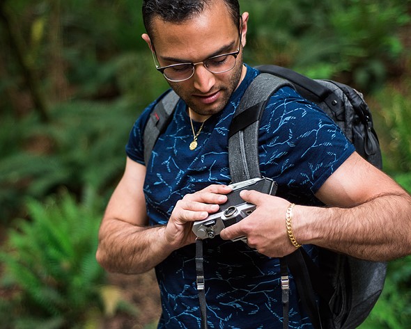 person attaches camera to backpack with camera clip