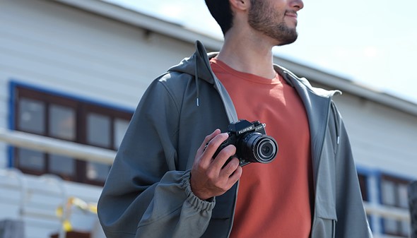 person holds fujifilm x-s20 in one hand in front of body