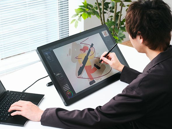 person sits at white desk drawing on wacom tablet display