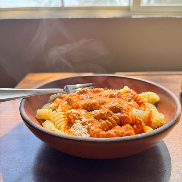 steam rises from a bowl of pasta with red sauce
