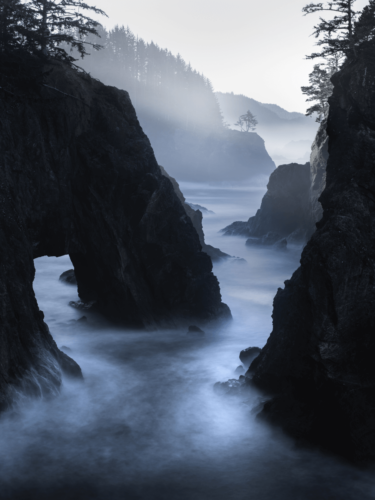 Dramatic coastal cliffs and ocean mist under soft twilight, an ideal subject for atmospheric photography.