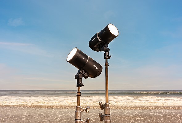 two profoto lights on stands in front of ocean