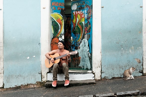 Shirtless man playing a guitar in a doorway