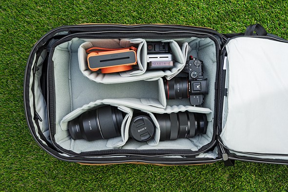 a camera backpack sits open with cameras and lenses inside