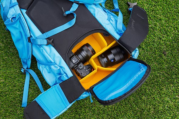 a camera is in a yellow camera insert in a blue backpack