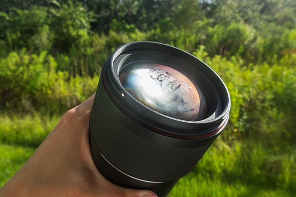 a hand holds a camera lens that is fogged up
