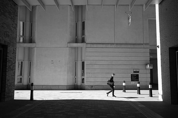 a person walks across an empty street with a blank building behind him