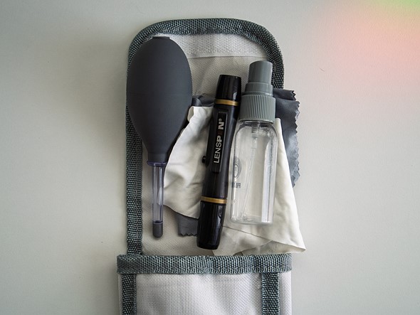 a selection of camera cleaning tools are placed on a white case on a white desk