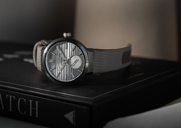 a silver watch sits on a black book