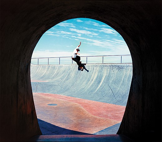 a skatboarder rides down a wall with blue sky above