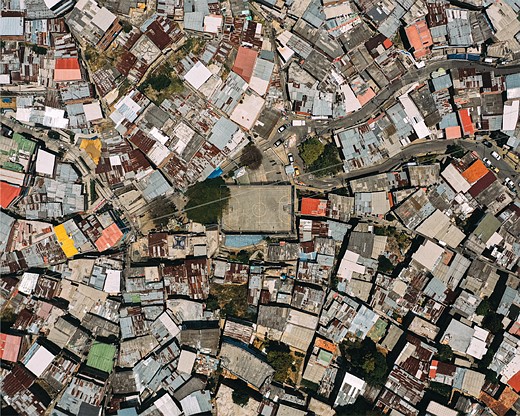 a soccer field sits in the middle of a jumble of buildings 