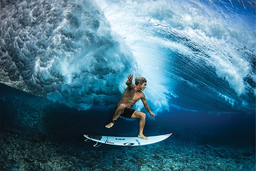 a surfer floats above their board under a wave