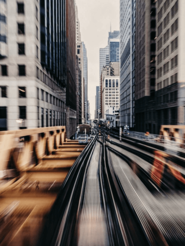 Blurred train tracks running through a cityscape, illustrating speed and depth using long exposure photography and motion blur techniques.