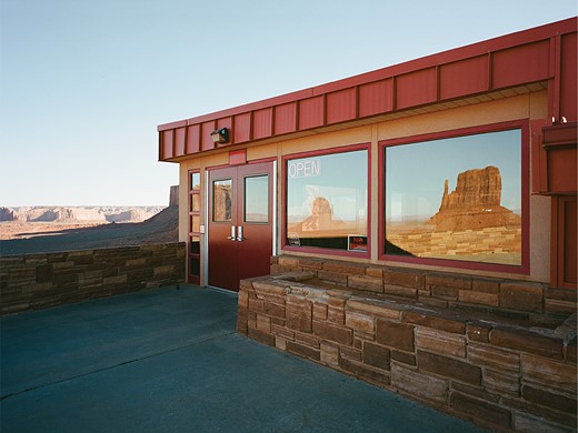 red cliffs reflect in the windows of a building in a desert