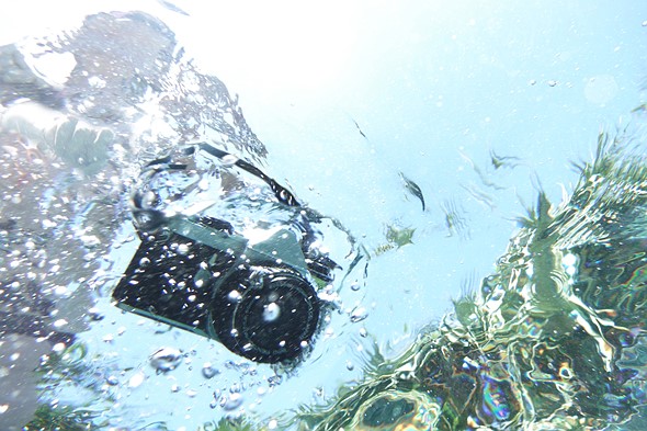 a camera is surrounded by water and bubbles from being dropped