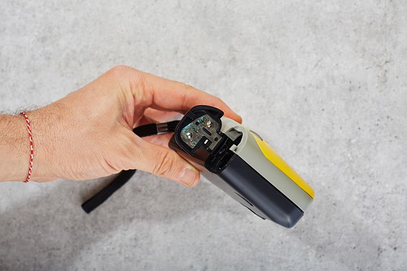 a hand holds a camera with corroded battery compartment exposed
