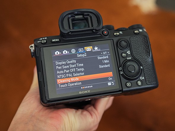 a hand holds a camera with the menu on the rear display