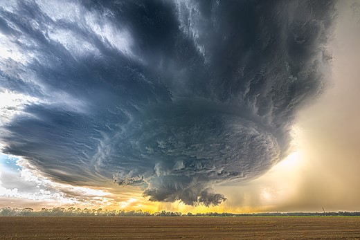 a large storm cloud looms over an open field