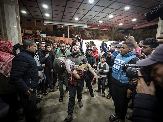 a man carries a body through a crowd