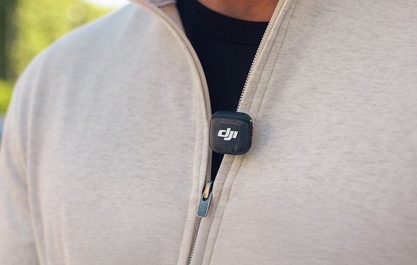 a tiny dji mic is clipped onto a tan zip sweatshirt