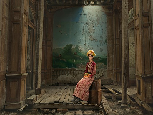 a woman with flower crown sits in an abandoned looking room