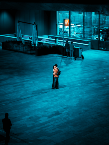Couple kissing after sunset in an intimate urban romance moment with warm sun flare.