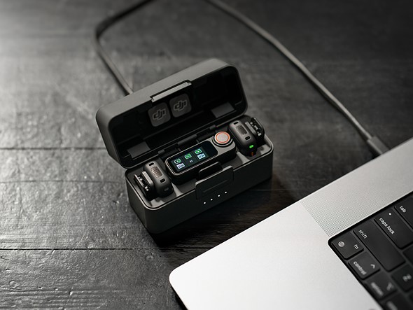 mics in a black charging case are plugged into a computer on a black table
