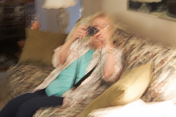 photo of a woman sitting on a couch holding up a camera
