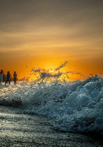 Ocean waves crash against the shore at sunset, with water splashing into a shape resembling a galloping horse, captured by Sirun Tang.